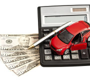Toy car, money and calculator over white. Concept for buying, re